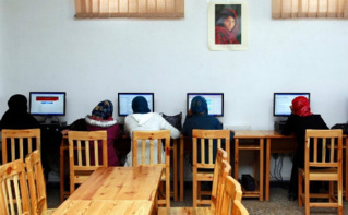 Lycéennes afghanes en salle informatique où figure "La femme afghane" qui incarne la souffrance et la dignité (cliché pris en 1984 par Steve McCurry). Image du domaine public.