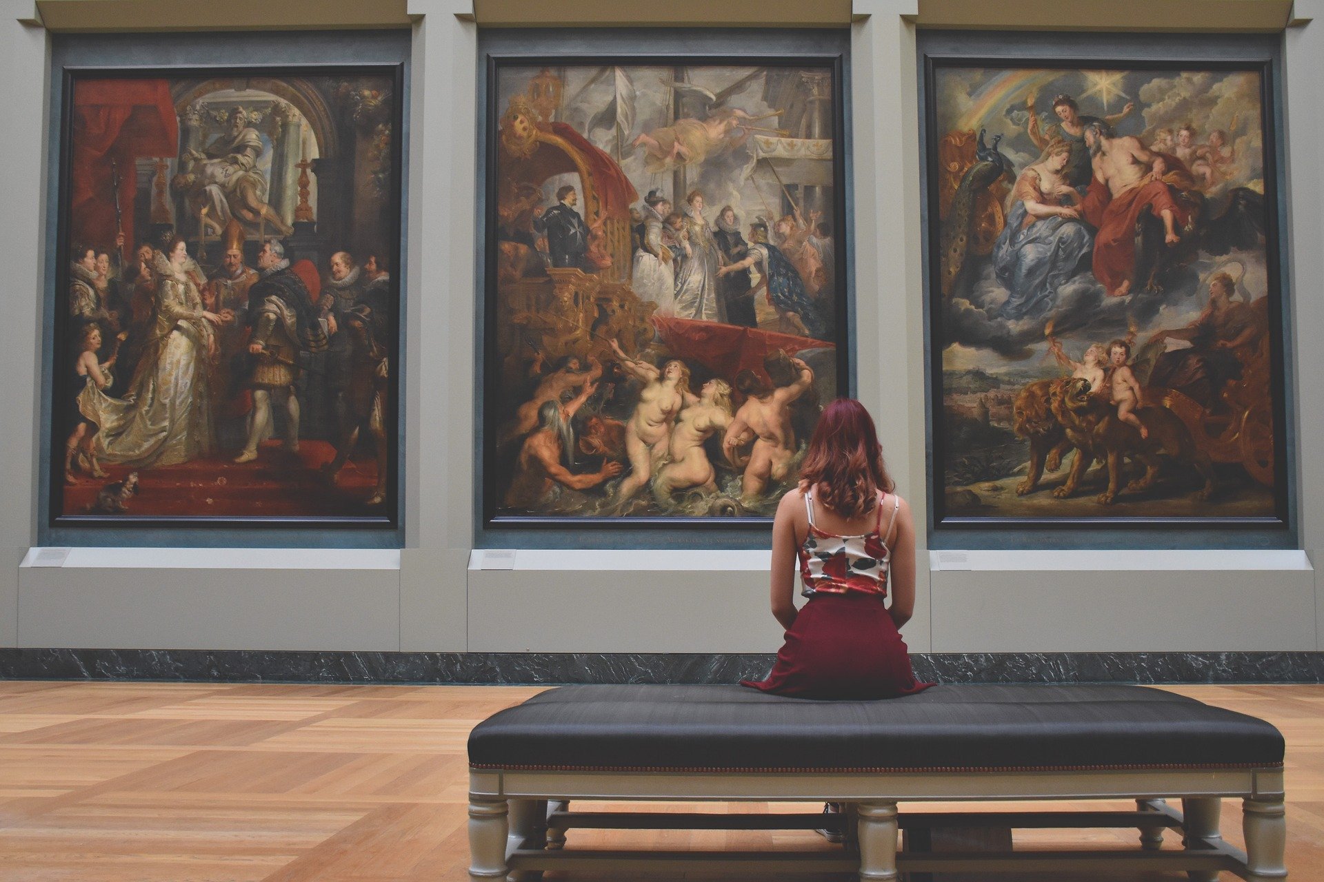 Une femme assise au musée du Louvre contemplant une triptyque, nous fait poser la question de notre propre consommation de biens culturels pendant cette période de confinement. (c)Pixabay